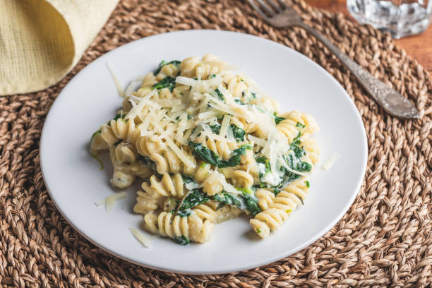 Creamy Pasta with Spinach and Ricotta Fusilli Pasta with Spinach and Ricotta Garnished with Grated Parmesan Cheese on White Plate spinach pasta stock pictures, royalty-free photos & images