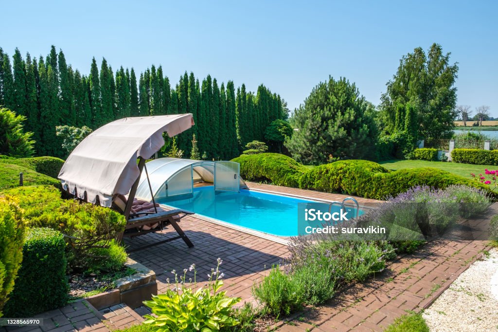 Swimming pool and garden with nicely trimmed bushes and garden swing in backyard Swimming pool and garden with nicely trimmed bushes and garden swing in backyard. Landscape design. High quality photo Architecture Stock Photo