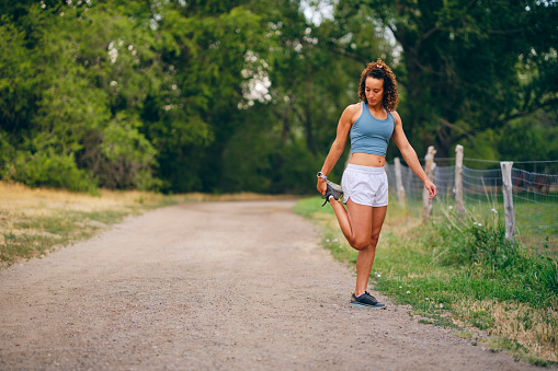 A woman athlete, stretches out her muscles before going on a run outdoors.