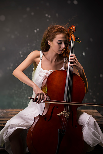 Red-haired girl in a white dress plays the cello.