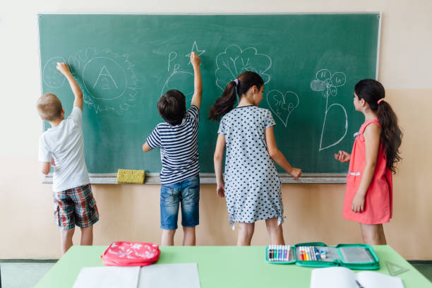 istock Children Writing On Blackboard At School 1328576422