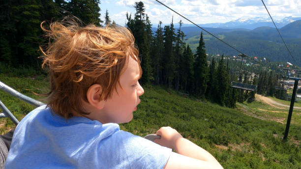 young boy relaxes on chairlift after hiking all day - children only tree area exploration freshness imagens e fotografias de stock