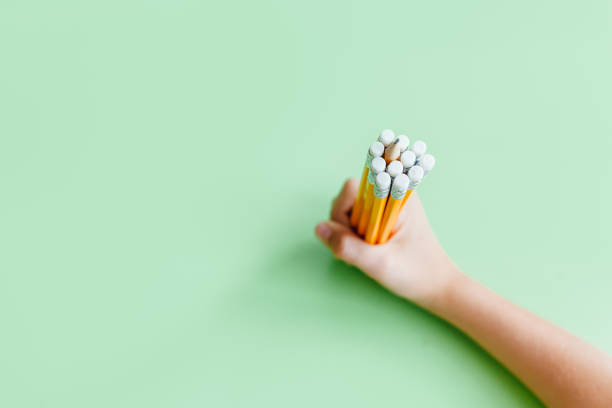 Portrait of little cute school kid boy with glasses. Beautiful happy child looking at the camera. Schoolboy making fun with a pen, holding in mouth and behind ear. Education concept