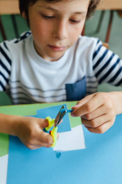 istock Boy Cutting Paper At School 1328577641