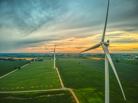 An aerial image of two wind turbines in rural farmland at sunset in Southwestern Ontario, Canada