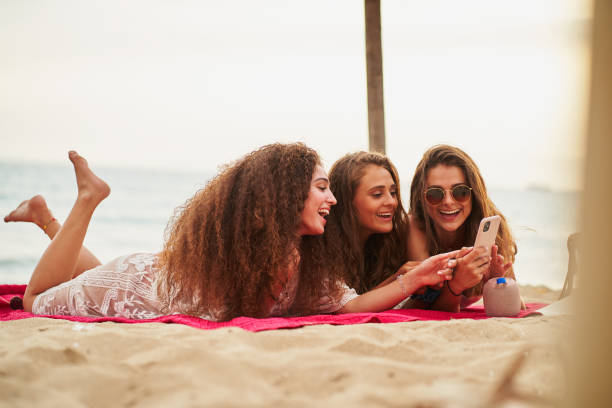 cheerful women playing music from phone on wireless speaker at beach - foton med speaker bildbanksfoton och bilder