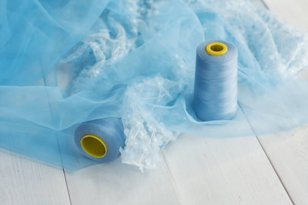 istock Blue satin fabric with threads on a wooden background with beads. 1328582163