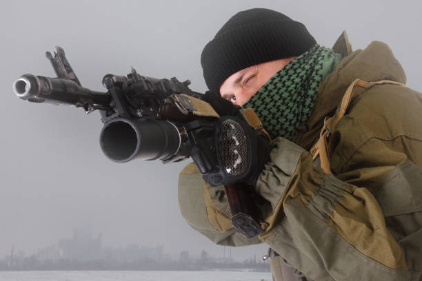 miliciano em uniforme padrão russo com rifle kalashnikov ak-47 com lançador de granadas debaixo de barril em campo de neve perto de objeto industrial abandonado - sniper rifle army soldier aiming - fotografias e filmes do acervo