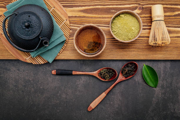 istock Black cast iron tea pot with herbal tea set up on dark stone background. 1328585044