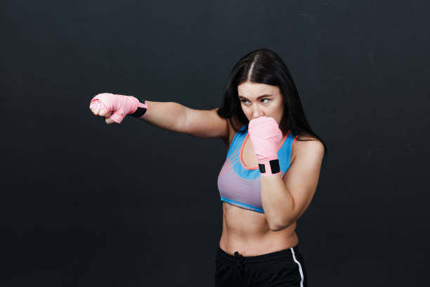 istock Sportsman woman boxer posing in training studio at black background. 1328586700