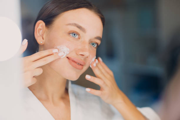 istock Young woman applying cosmetic white cream on her face 1328586776