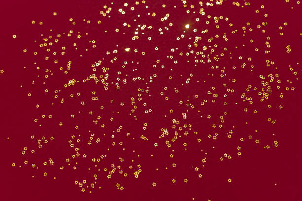 istock Gold glitter stars on a dark red background 1328586882