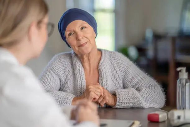 A cancer patient smiles while discussing with her doctor in a medical office.