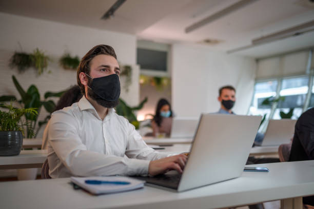 istock Front view of Caucasian male office worker in face mask working on a computer 1328588041