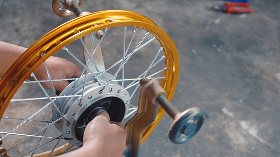 Technician man working motorcycle wheel has spokes weave up on mechanic new steel wheel, Motorcycle spokes wheel alignment machine tool