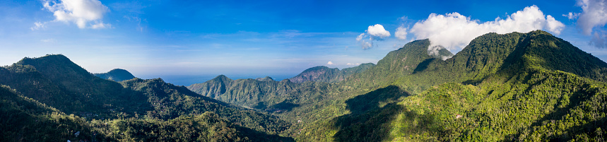Landscape in panoramic mode of the mountain range located in the province of Karangasem near Amed village in Bali and facing the ocean over the horizon.