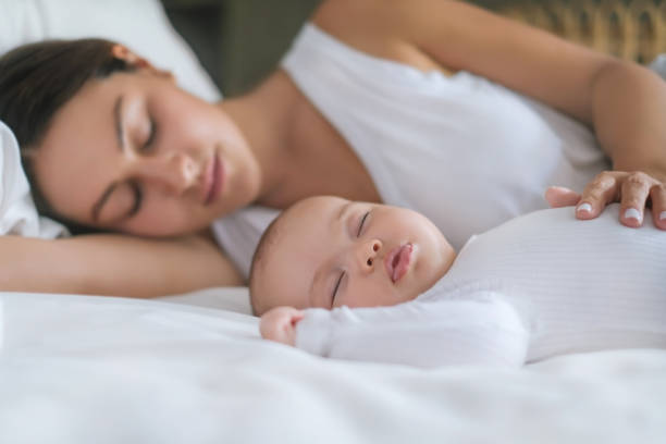 istock Mother And Newborn Baby Sleeping Side by Side 1328594781