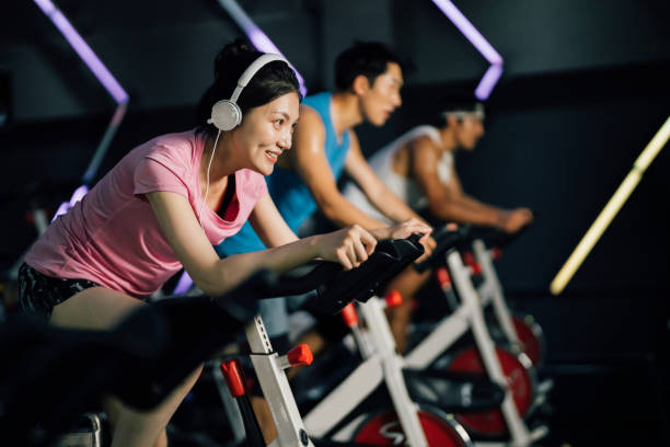 체육관에서 고정 자전거를 타고 아시아 젊은 여자. 건강 및 피트니스 개념. - bicycle women cycling gym 뉴스 사진 이미지