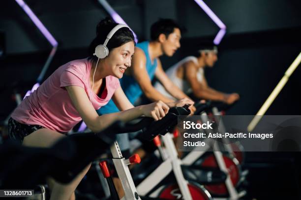 Asian Young Woman Riding Stationary Bike At Gym Health And Fitness Concept Stock Photo - Download Image Now