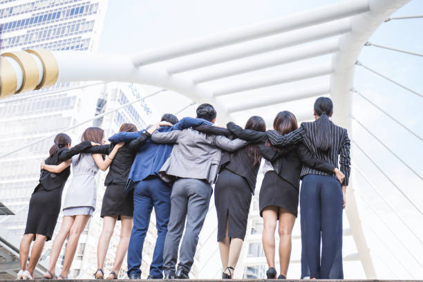 groupe de gens d’affaires à l’extérieur de leur entreprise, se tenant la main levée célébrer le succès de l’entreprise. le travail d’équipe s’associe à un concept de plein air réussi. - success businessman corporate business ecstatic photos et images de collection