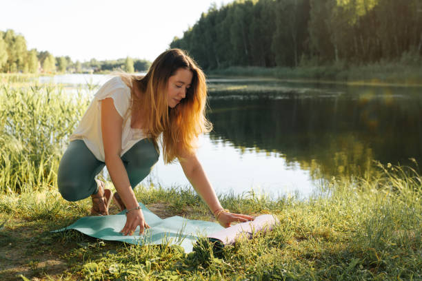 Pretty young woman practicing yoga outdoors. Slim fitness woman rolling yoga mat for workout on the beach. Beautiful yogi woman about to train in nature. Healthy lifestyle concept, yoga and meditation mujer bastante joven practicando yoga al aire libre. slim fitness mujer rolling yoga mat para el entrenamiento en la playa. hermosa mujer yogui a punto de entrenar en la naturaleza. concepto de estilo de vida saludable, yoga y meditación