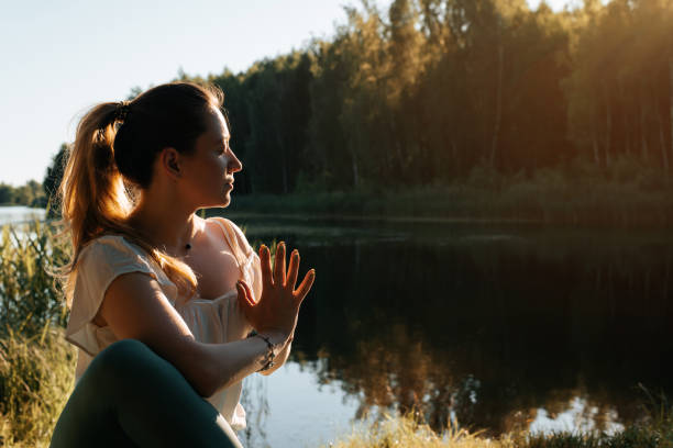 meditação de yoga ao ar livre. retrato de uma jovem praticando yoga na natureza. yogi sentado de olhos fechados na margem do lago ao pôr do sol. conceito de meditação, sage marichi pose - pose of sage marichi - fotografias e filmes do acervo