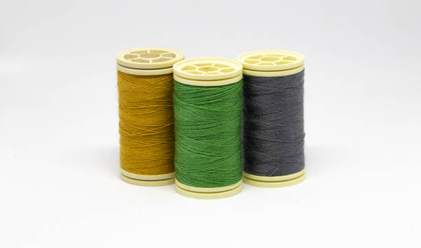 Three spools of thread with different yellow hues together with love material on them