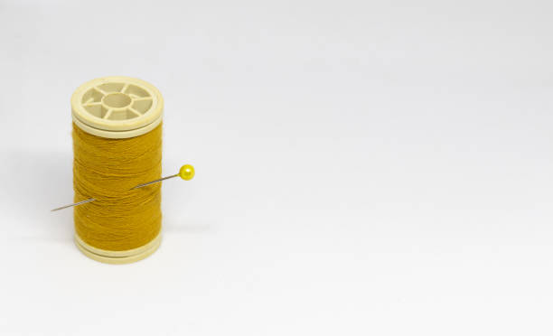 istock Spool of a yellow color thread on an isolated white background 1328610983