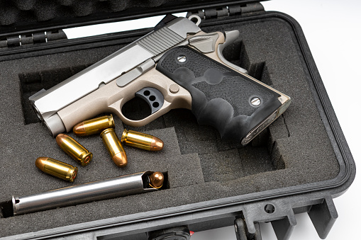 Automatic handgun and bullets in a plastic hard case on white background