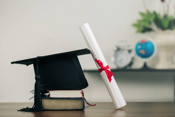 A mortarboard on books and graduation scroll on the desk.education learning concept