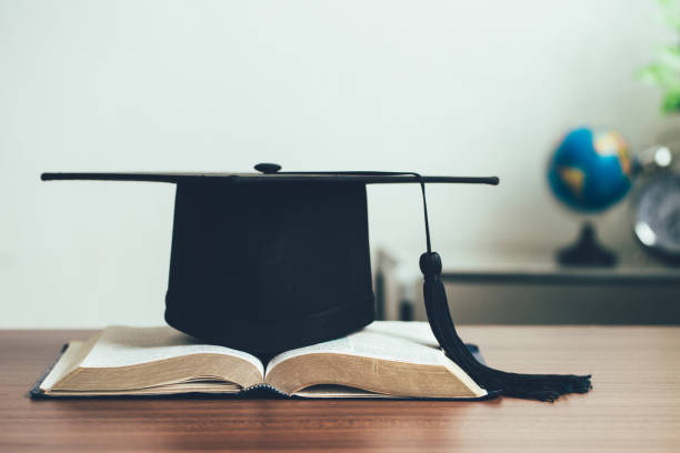 un tablero de mortero y un rollo de graduación en libros abiertos en el concepto de aprendizaje desk.education - old master fotografías e imágenes de stock