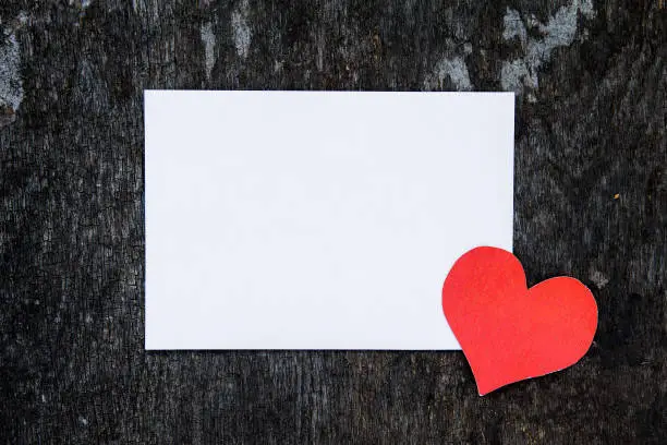 Empty Paper with a Red Heart Shape on the Grunge Wooden Background closeup