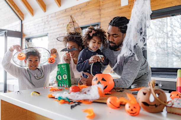 African American family making Halloween decorations at home. Happy black parents and their kids enjoying while making decorations for Halloween at home. jack o lantern photos stock pictures, royalty-free photos & images