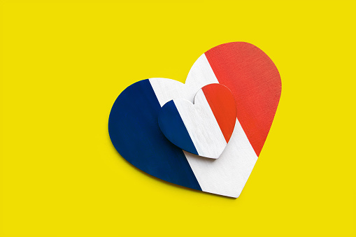 wooden heart painted in colors of flag of Italy green, white and red on yellow background diagonally, concept