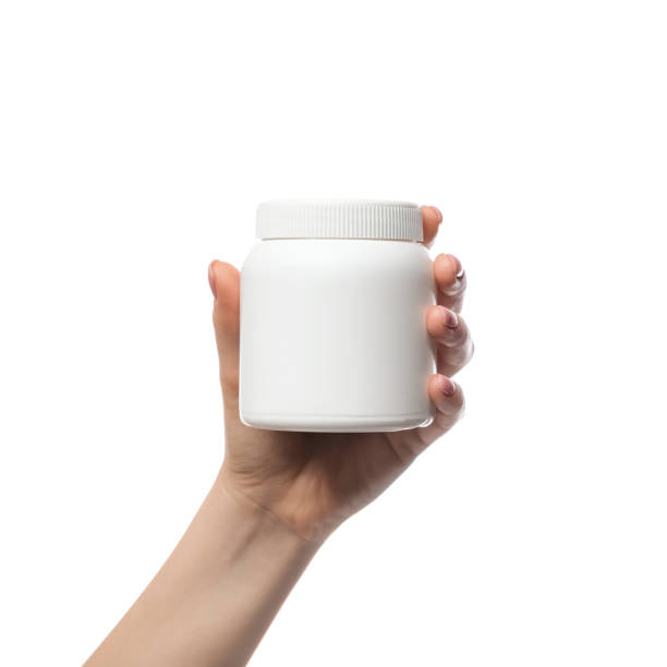 A white plastic jar, a container in a woman's hand. There is a space for advertising or a logo. Template for a commercial product. stock photo