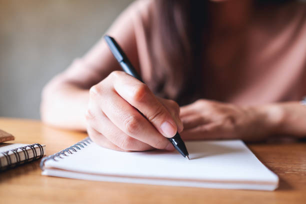 istock a woman writing on notebook on wooden table 1328628877