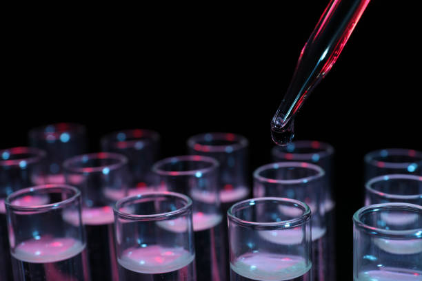Dripping reagent into test tube on black background, closeup. Laboratory analysis