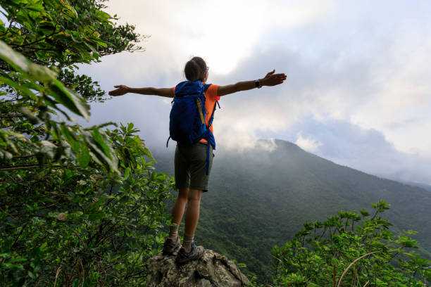 istock Cheering young woman hiker open arms on mountain peak 1328629866