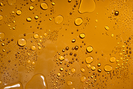 Water drops on the dark yellow background.Wet yellow surface for design
