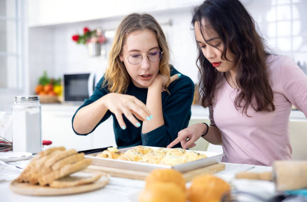 istock Beautiful baker making pastries, Cute happy two Women have fun a bread making classroom and use their hands to slap the dough together to make cakes together in the home kitchen. 1328632441