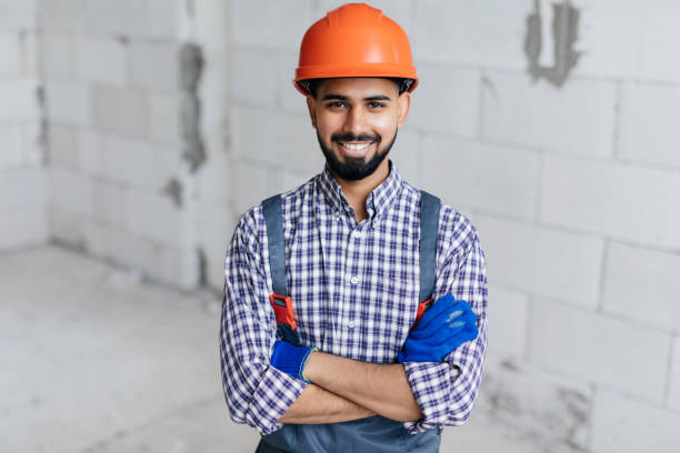istock Young worker reassure holds autoclaved aerated bricks in construction site, Concept proposes to use autoclaved aerated bricks in construction of houses. 1328632570