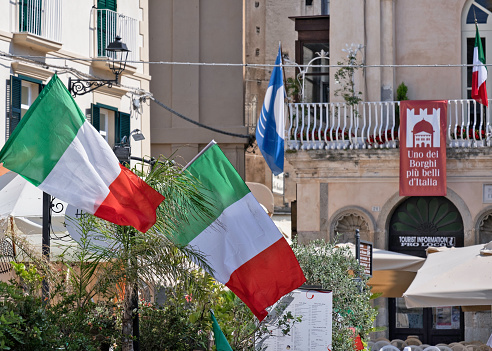 Tropea, Italy - June 14, 2021: Detail of the Piazza Ercole with the Tourist Information office and Italian national flags in Tropea, Italy.