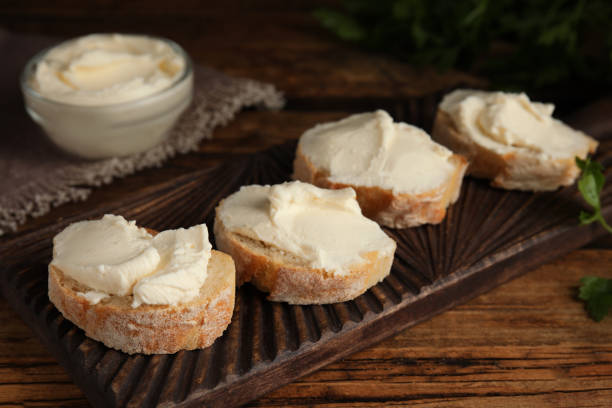 istock Bread with cream cheese on wooden board, closeup 1328637069
