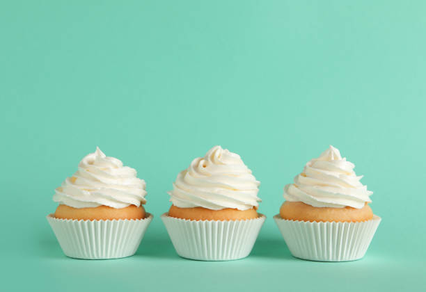 istock Delicious cupcakes with white cream on turquoise background. Space for text 1328637144