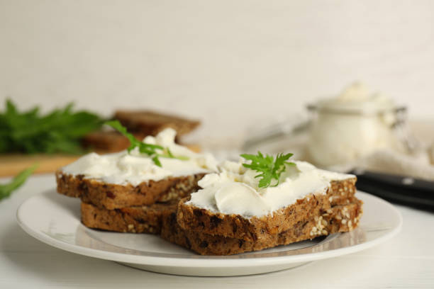 istock Bread with cream cheese and arugula on white wooden table 1328637254