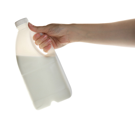 Woman holding gallon bottle of milk on white background, closeup