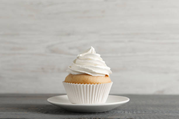 istock Delicious cupcake with cream on grey wooden table 1328638473