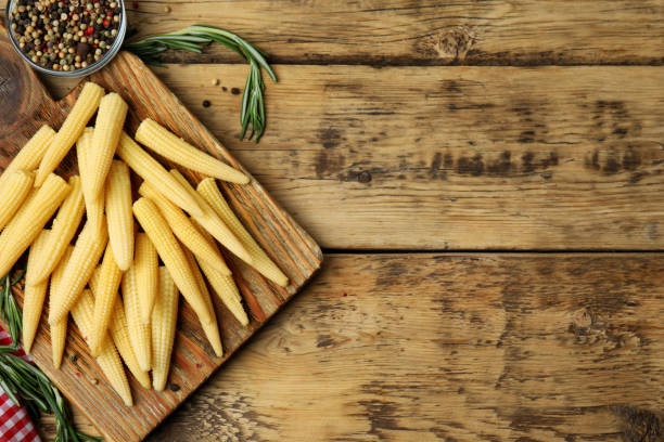 istock Fresh baby corn cobs and spices on wooden table, flat lay. Space for text 1328638541