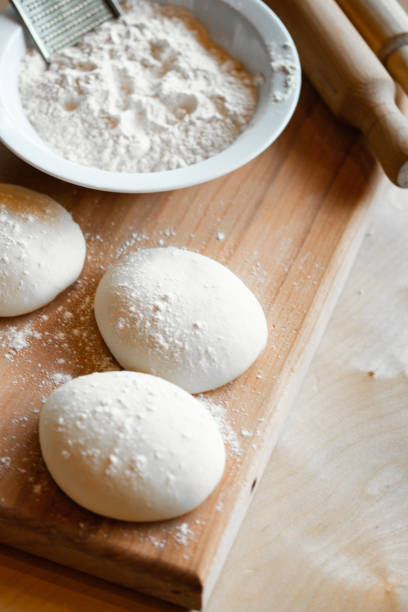 istock Cooks roll dough for baking, pieces of raw dough on wooden Board 1328641704