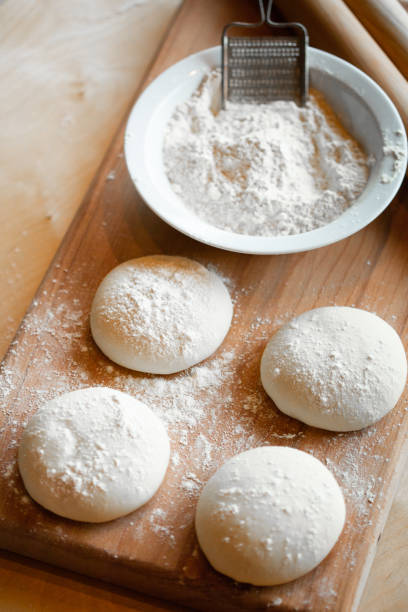 istock Cooks roll dough for baking, pieces of raw dough on wooden Board 1328641977